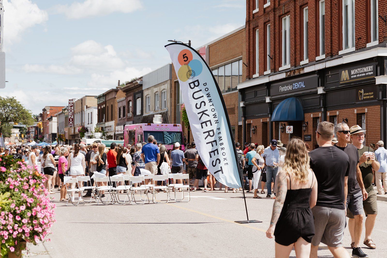Crowds filling the closed downtown street between the shopfronts, with festival flags overhead.