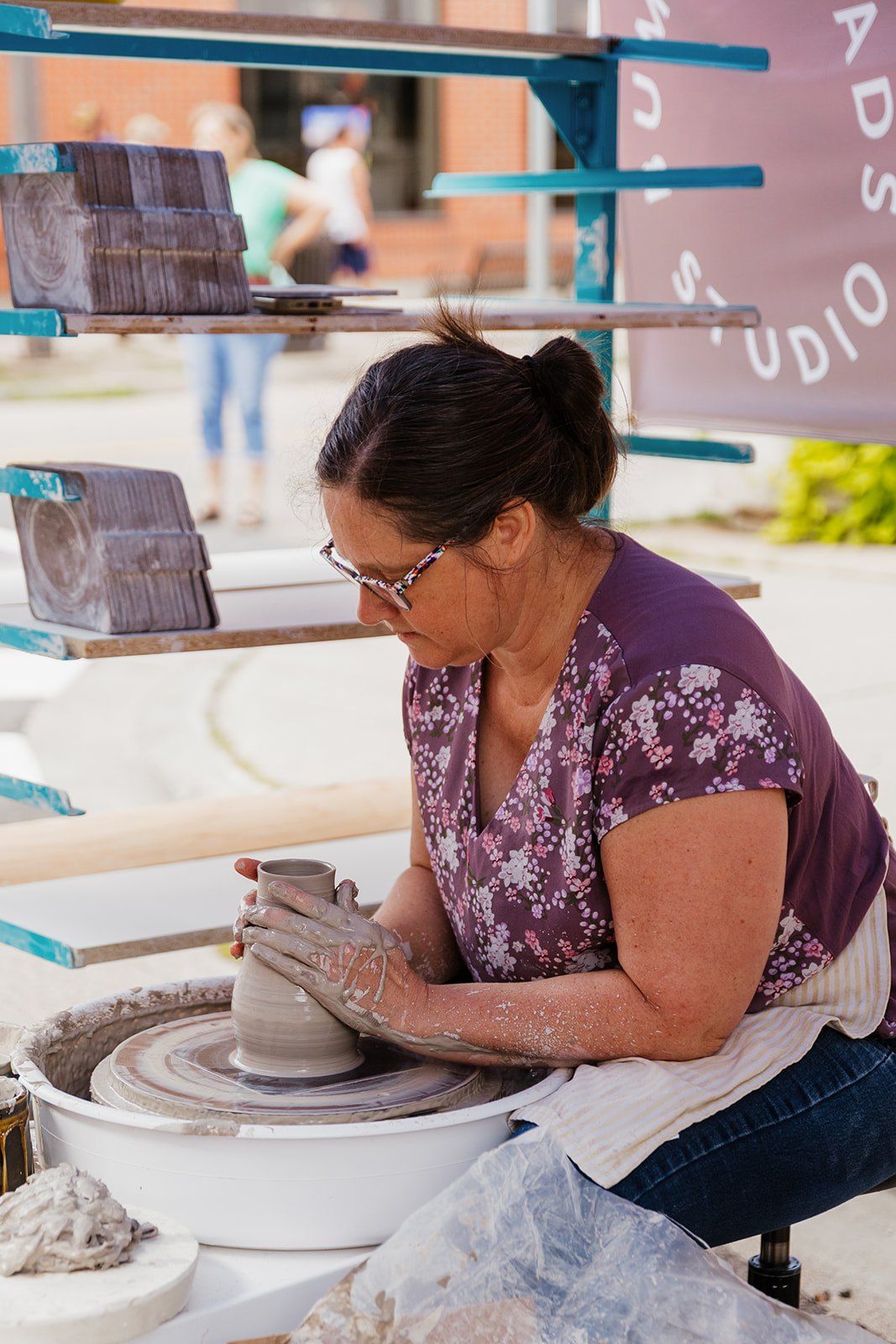 A potter throwing a bowl on a wheel at a demonstration stall.