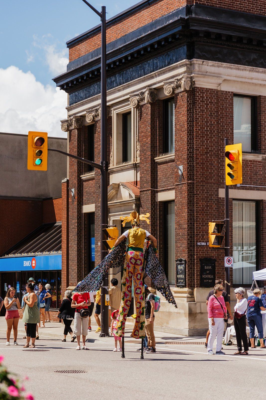 Stilt-walkers in costume making their way down the closed street past shopfronts.