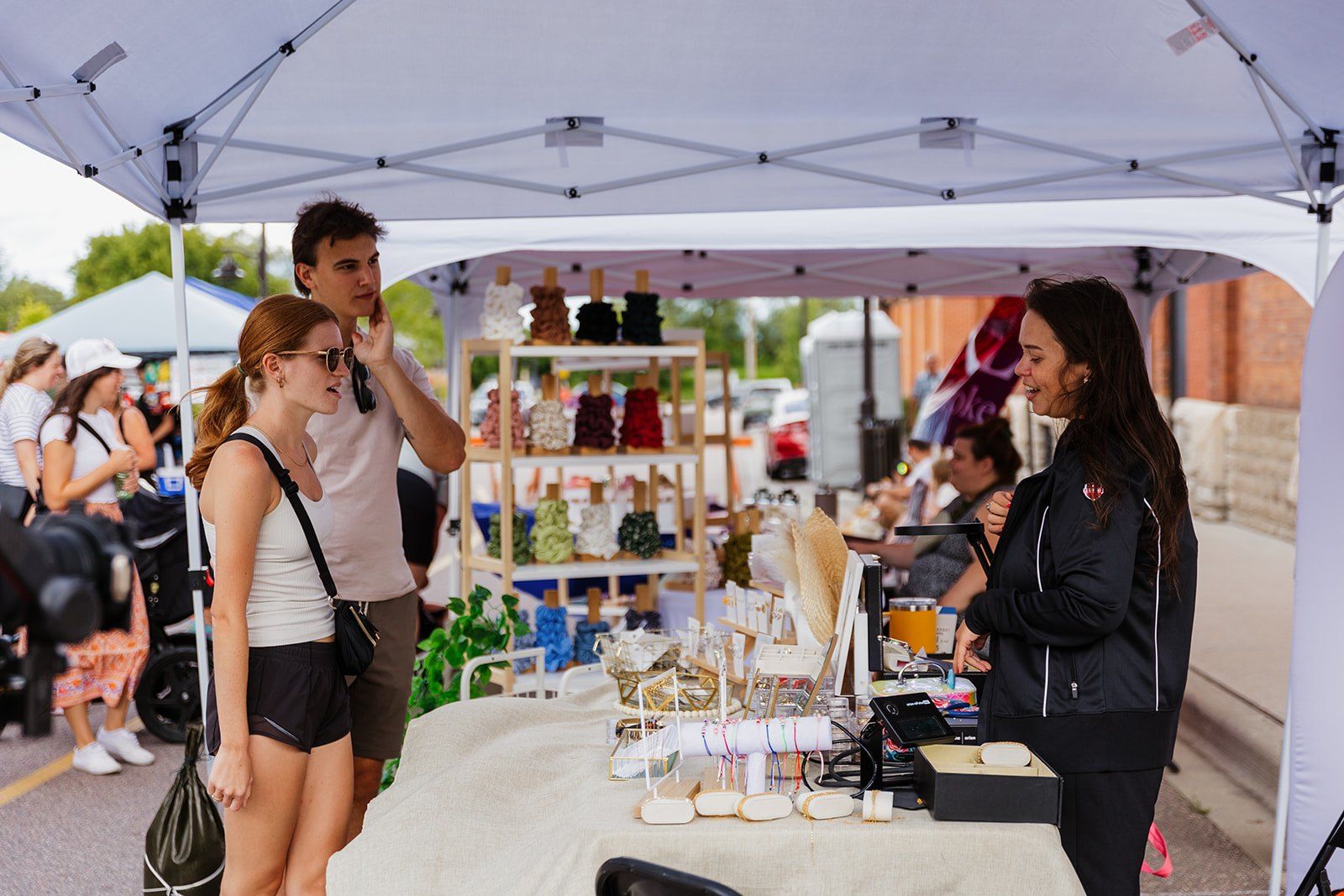 Shoppers browsing a vendor's tent at the market stalls along the street.
